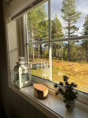 a window sill with a candle and a bottle on it at Cozy apartement near Besseggen with a nice outdoor area! in Randsverk