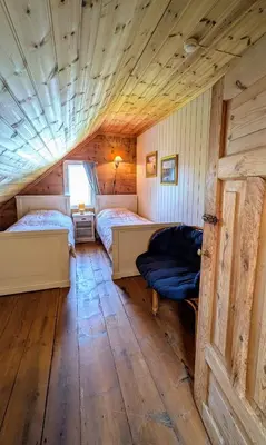two beds in a room with a wooden ceiling at Dønhaug Gjestegard in Uskedalen