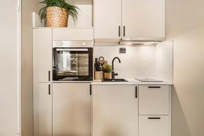 a kitchen with white cabinets and a microwave at Dinbnb Apartments I Explore Bergen! I 650m To Bryggen I Easy Check-in in Bergen