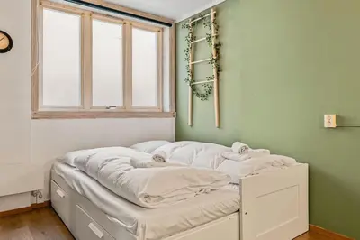 a bed with white sheets in a room with a window at Dinbnb Apartments I Explore Bergen! I 650m To Bryggen I Easy Check-in in Bergen