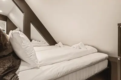 a bed with white sheets in a room at Dinbnb Apartments I Penthouse 250m From City Center I Privat Balcony in Bergen