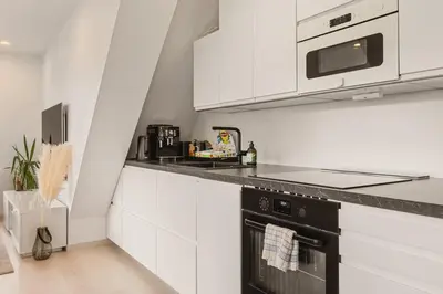 a kitchen with white cabinets and a black stove top oven at Dinbnb Apartments I Penthouse 250m From City Center I Privat Balcony in Bergen