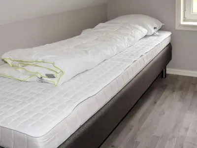 a bed with white sheets on top of it at 9 person holiday home in Åram in Sandvik