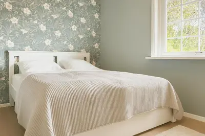 a white bed in a bedroom with a floral wallpaper at Hus med panoramutsikt i Bud in Bud