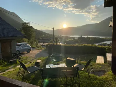 a table and chairs in a yard with the sunset at Hyggelig og velutstyrt leilighet i Lom sentrum in Lom