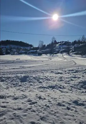 a field covered in snow with the sun in the sky at Leilighet Vingnes in Lillehammer
