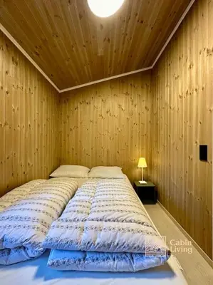 a large bed in a room with a wooden wall at New large cabin with sauna in Hafjell in Nordseter