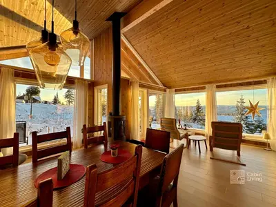 a dining room with a table and chairs and windows at New large cabin with sauna in Hafjell in Nordseter
