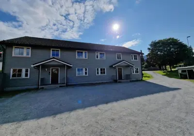 a large gray house with a driveway in front of it at Rom 6 sentralt i Sogndal in Sogndal