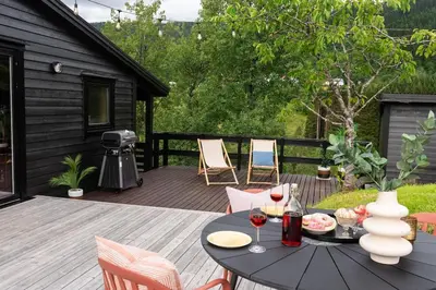 a patio with a table and chairs on a deck at Lite hus 40 minutter unna Bergen in Bjørkheim