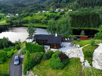 a house on a hill next to a lake at Lite hus 40 minutter unna Bergen in Bjørkheim