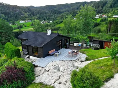 a black cabin with a deck on a rock at Lite hus 40 minutter unna Bergen in Bjørkheim