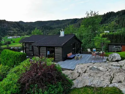 a small cabin with a deck on a mountain at Lite hus 40 minutter unna Bergen in Bjørkheim