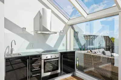 a kitchen with a large window and a stove at 7 min to Ski Championship, Glass front house, Terrace in Trondheim
