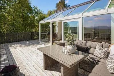 a patio with a table and a glass house at 7 min to Ski Championship, Glass front house, Terrace in Trondheim