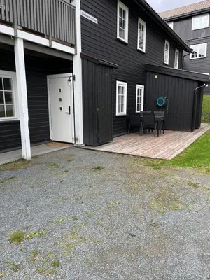 a black building with a patio and a white door at Flott Leilighet i stølen oppdal for 6 personer, ski in, ski out in Oppdal