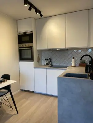 a kitchen with white cabinets and a table and a counter at Plaza Havstad in Trondheim