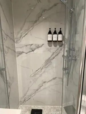 a shower with two bottles of soap on a marble wall at Plaza Havstad in Trondheim