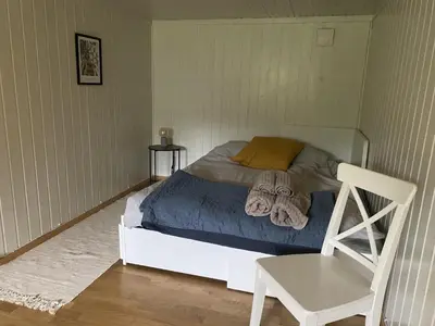 a bedroom with a bed with a chair and a table at Villekulla - Koselig hus med jazzuci i Hamar in Hamar