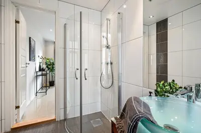 a bathroom with a shower and a blue tub at Charming apartment in Sandviken in Bergen