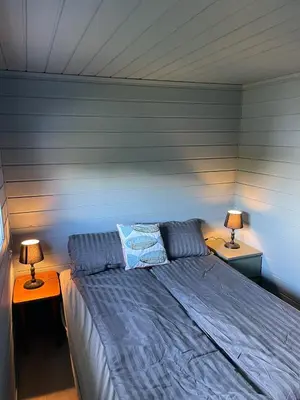 a bed in a room with two lamps on tables at Hytte ved sjøen med båtutleige in Kvalsvik