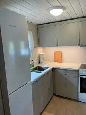 a kitchen with white cabinets and a white refrigerator at Hytte ved sjøen med båtutleige in Kvalsvik