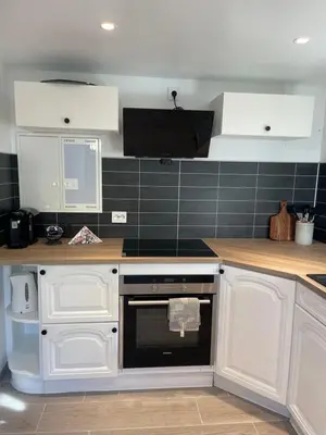 a kitchen with white cabinets and a black oven at Charming Modern Apartment Close to Moa & Ålesund in Ålesund