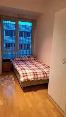 a bedroom with a bed and a large window at Leilighet ved City Lade in Trondheim