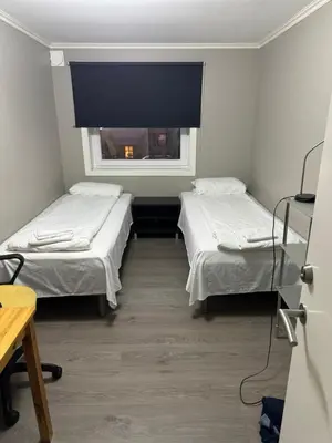 two beds in a room with a window at Alesund bedroom with shared shower in Ålesund