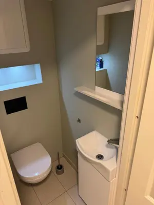 a small bathroom with a toilet and a sink at Alesund bedroom with shared shower in Ålesund