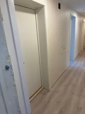an empty hallway with white walls and a door at Alesund bedroom with shared shower in Ålesund