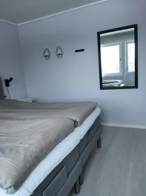 a white bedroom with a bed and a mirror at Fjellhagen - Geirangerfjord view in Hellesylt
