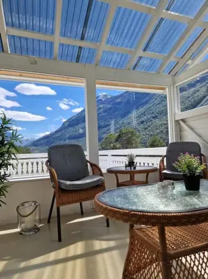 a conservatory with two chairs and a table and windows at Fjellhagen - Geirangerfjord view in Hellesylt