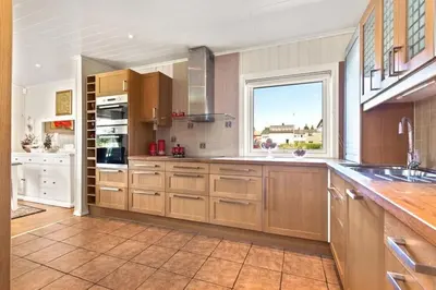 a large kitchen with wooden cabinets and a window at Luksuriøs enebolig ved Granåsen til Ski-VM 2025 in Trondheim