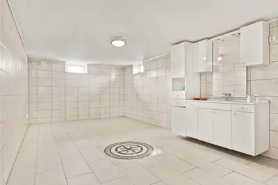 a bathroom with white cabinets and a tile floor at Luksuriøs enebolig ved Granåsen til Ski-VM 2025 in Trondheim