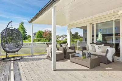 a porch with couches and a chair and a swing at Luksuriøs enebolig ved Granåsen til Ski-VM 2025 in Trondheim