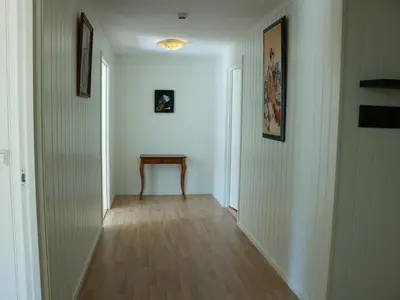 a hallway with white walls and a table on a wooden floor at Trysil sentrum leilighet in Trysil
