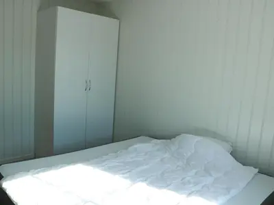 an unmade bed in a white room with a window at Trysil sentrum leilighet in Trysil