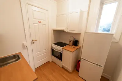 a small kitchen with white cabinets and a white refrigerator at Leilighet i Ålesund Sentrum in Ålesund