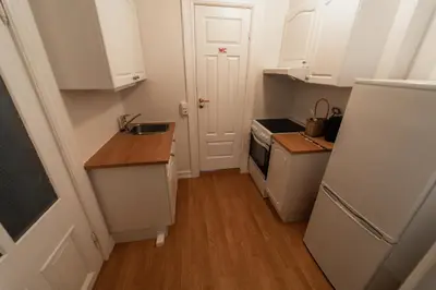 a kitchen with white cabinets and a sink and a refrigerator at Leilighet i Ålesund Sentrum in Ålesund