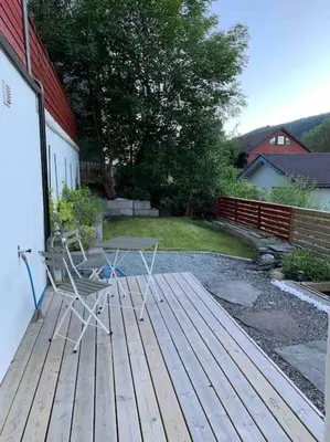 a table and chairs sitting on a wooden deck at Moderne og fullt utstyrt 3-rom hageleilighet sentrum nær in Bergen