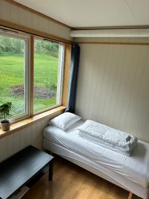 a small room with a bed and two windows at Damehuset in Sæbø