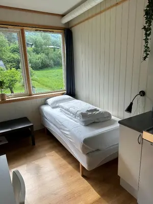 a small bedroom with a bed and a window at Damehuset in Sæbø