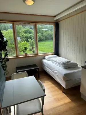 a small bedroom with a bed and a window at Damehuset in Sæbø