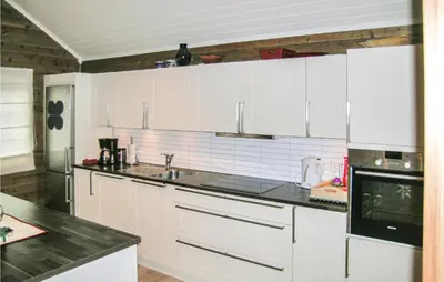 a kitchen with white cabinets and a black counter top at Nice Home In Straumgjerde With Wifi in Brunstad