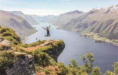 a person jumping off of a cliff over a lake at Nice Home In Straumgjerde With Wifi in Brunstad