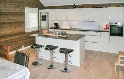 a kitchen with white cabinets and a counter with stools at Nice Home In Straumgjerde With Wifi in Brunstad