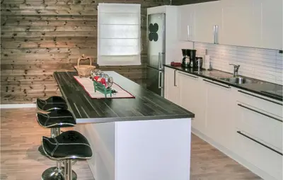 a kitchen with a counter with two stools in it at Nice Home In Straumgjerde With Wifi in Brunstad