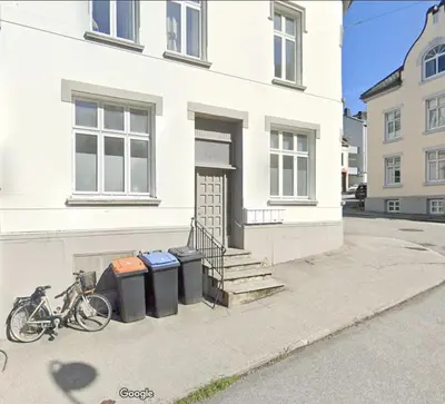 a bike parked next to a building with two trash cans at Downtown free parking cozy apartment in Ålesund