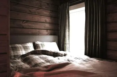 an unmade bed in a room with a window at Tømmerhus i Geiranger Sentrum med panorama utsikt in Geiranger